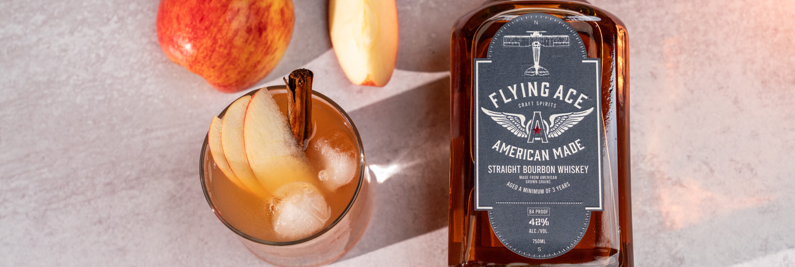 best bourbon mixers, best mixers for bourbon, flying ace whiskey on a table with apple cider cocktail and apple slices 