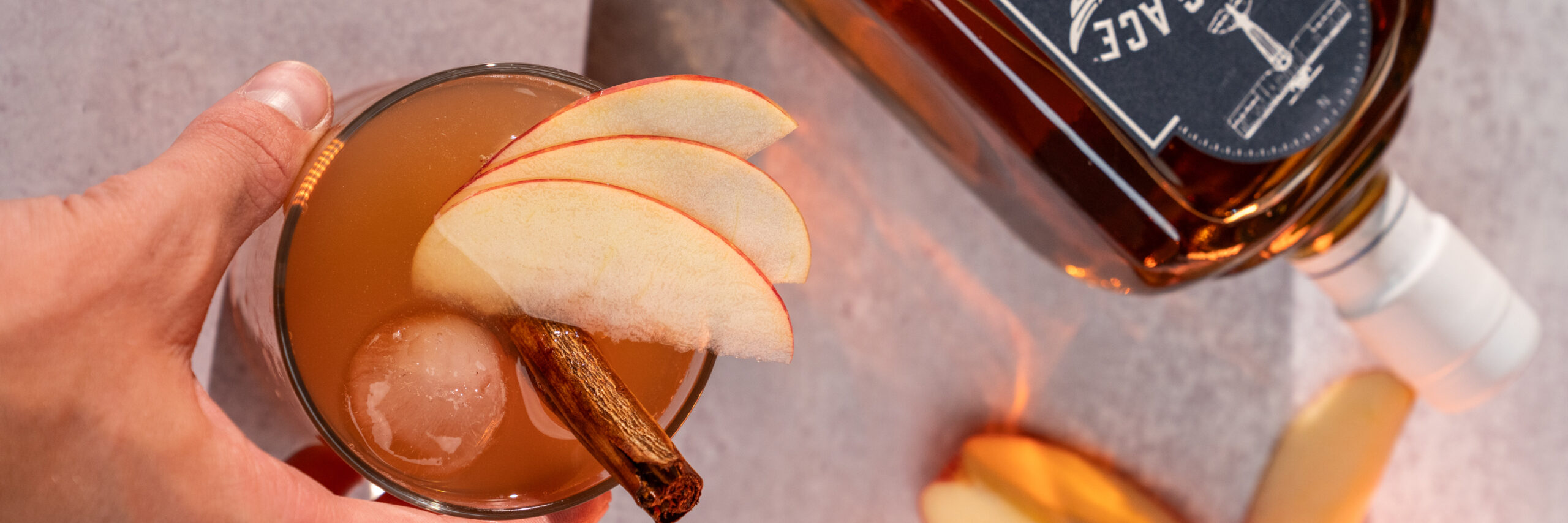 best mixers for bourbon, bourbon mixers, hand setting cocktail with apple slices down on table